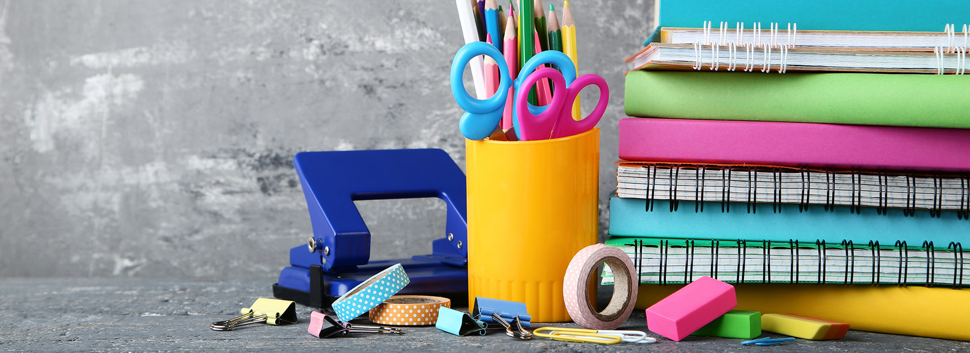 School supplies with books and notebooks on grey background